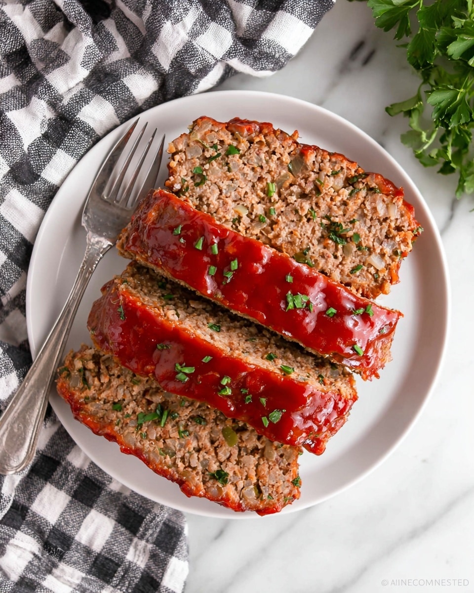 The image shows three thick slices of meatloaf on a white round plate. Each slice has a textured, light brown inside with small bits of onion visible, and the top of each slice is covered in a shiny, smooth red sauce. Small green herb pieces are sprinkled over the sauce and meatloaf. The plate is set on a white marbled surface with a black and white checkered cloth partly visible in the background. A silver fork rests on the left side of the plate, its handle lying on the cloth. There are some green leaves in the upper right background. Photo taken with an iphone --ar 4:5 --v 7