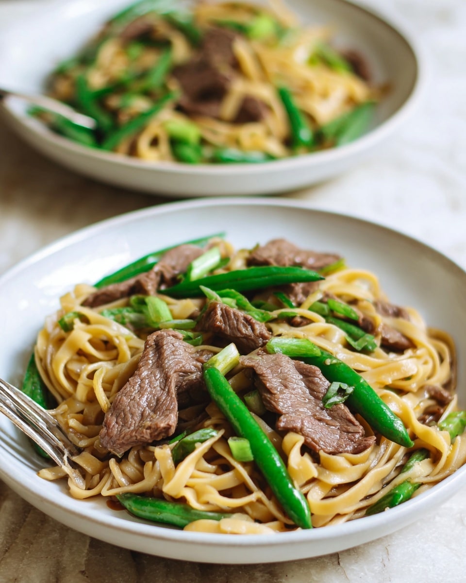 Two white plates filled with a layered beef noodle dish are placed on a white marbled surface. The front plate shows thick light brown noodles forming the base layer, topped with tender slices of cooked brown beef scattered evenly. Bright green green beans and chopped green onions add fresh color, placed throughout the dish in between the beef and noodles. A shiny fork rests on the edge of the front plate. The background plate mirrors the same layering but is out of focus. photo taken with an iphone --ar 4:5 --v 7