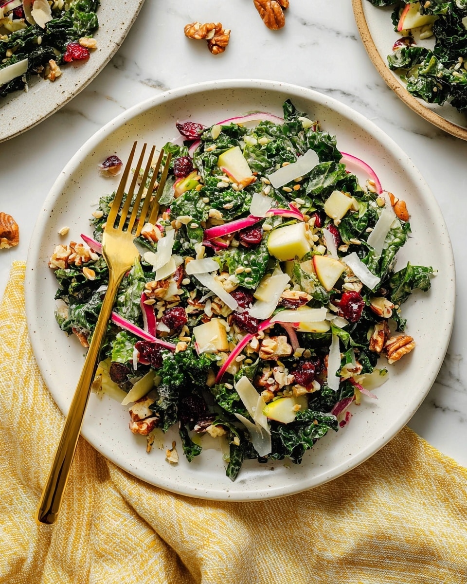 A white plate filled with a fresh salad layered with deep green kale leaves, thinly sliced red onion rings, and small chunks of pale yellow apple. Scattered throughout are toasted brown nuts and seeds, bright red dried cranberries, and light beige cooked grains, all mixed with thin shavings of white cheese. A gold fork rests on the left side of the plate, with some salad pieces spilling slightly onto the edge. The setting is on a white marbled surface with additional salad pieces and a yellow striped cloth nearby. photo taken with an iphone --ar 4:5 --v 7