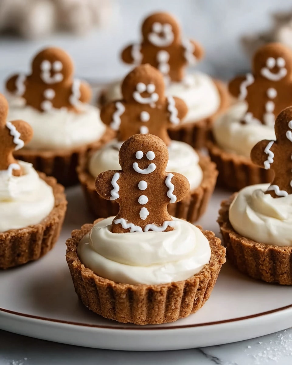 The image shows several gingerbread tartlets on a white plate with a thin brown rim, placed on a white marbled surface. Each tartlet has a golden-brown crust with ridged edges forming the bottom layer. The middle layer is filled with smooth, white cream that is slightly puffed up in the center. Standing upright in the cream is a small brown gingerbread cookie shaped like a person, decorated with white icing for eyes, smile, buttons on the torso, and wavy patterns on the arms and legs. The tartlets are arranged close together, filling the plate, with some tartlets slightly blurred in the background. Photo taken with an iphone --ar 4:5 --v 7