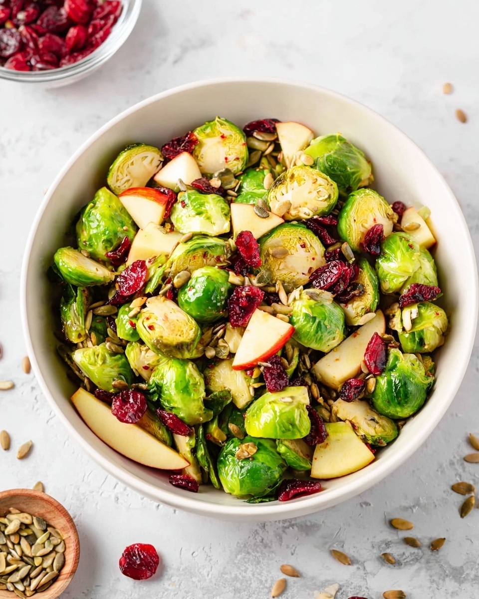 A white bowl is filled with a bright salad showing two main layers: the bottom layer is a mix of green Brussels sprouts and light yellow diced apples, while the top layer includes dark red dried cranberries and light brown toasted sunflower seeds scattered on top. A wooden spoon holds a scoop of the salad in the foreground, featuring mostly Brussels sprouts, cranberries, sunflower seeds, and a few green leafy bits. The background has a white marbled texture with a blue cloth partially visible. Photo taken with an iphone --ar 4:5 --v 7