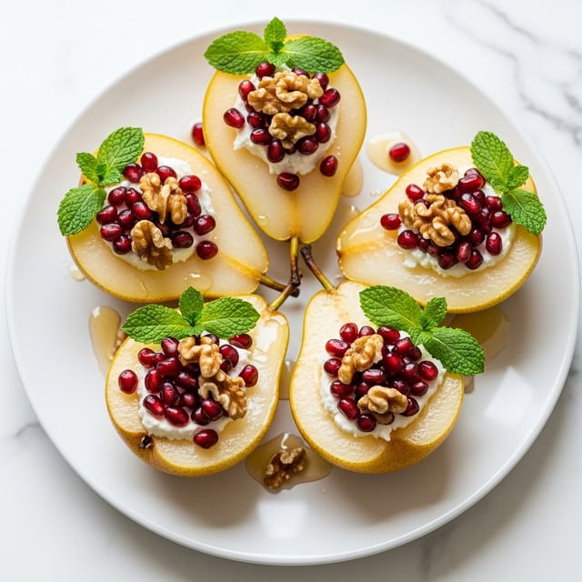 A white plate holds four pear halves with golden yellow skin and light cream flesh, each filled with a soft white cheese layer. On top of the cheese are scattered dark red pomegranate seeds and crunchy walnut pieces, creating a mix of red and brown colors. Each pear half is garnished with fresh green mint leaves, adding a touch of brightness. The plate sits on a white marbled surface, and a drizzle of light honey or syrup glistens around the pears, adding shine and moisture to the scene. Photo taken with an iphone --ar 4:5 --v 7