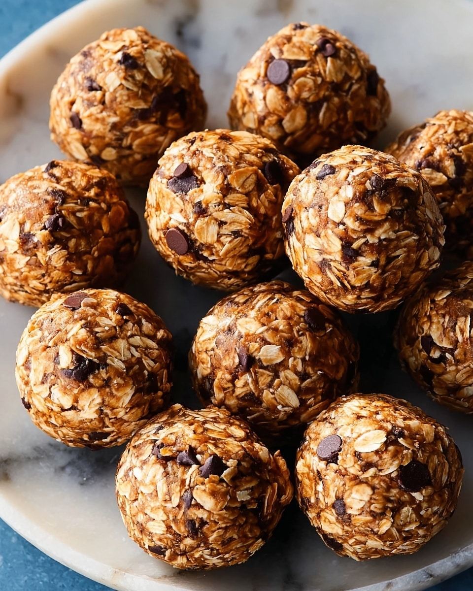 A group of round energy balls, each about the size of a small cookie, are displayed on a white plate. The balls have a rough texture with visible oat flakes mixed with small dark chocolate chips scattered throughout. The colors are warm and natural, with the oats creating a light brown and beige base, while the chocolate chips add small dark brown spots on each ball. The plate has a subtle marbled white pattern underneath, creating a clean and fresh look. The energy balls are packed closely, filling the plate almost completely. photo taken with an iphone --ar 4:5 --v 7