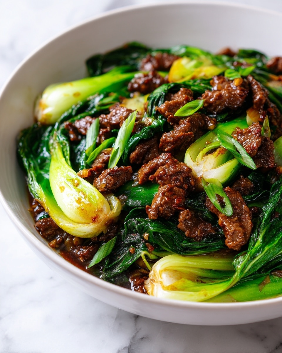 The dish shows a bowl filled with glossy pieces of cooked beef and bright green bok choy. The beef pieces are brown and tender, spread evenly through the bowl. The bok choy has thick, light green stems and dark green leaves, both cooked but still shiny and fresh looking. The ingredients are mixed well, sitting in a light brown sauce that gives a moist and rich texture. The bowl is white with a thin brown rim, placed on a white marbled surface. photo taken with an iphone --ar 4:5 --v 7