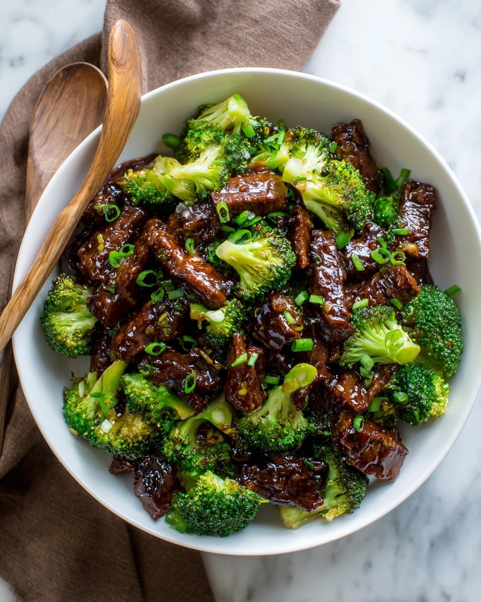 The dish shows a close-up of a white bowl filled with beef and broccoli stir-fry. There are many small, dark brown beef pieces coated in a glossy sauce, mixed with bright green broccoli florets. The beef pieces are rectangular, tender-looking, and have a shiny, slightly sticky texture, while the broccoli has a fresh, crisp look with tiny buds visible. Small bits of green onions and sesame seeds are scattered over the dish, adding a little color contrast. A wooden spoon is partially visible on the left side, placed inside the bowl against the white marbled surface background. photo taken with an iphone --ar 4:5 --v 7