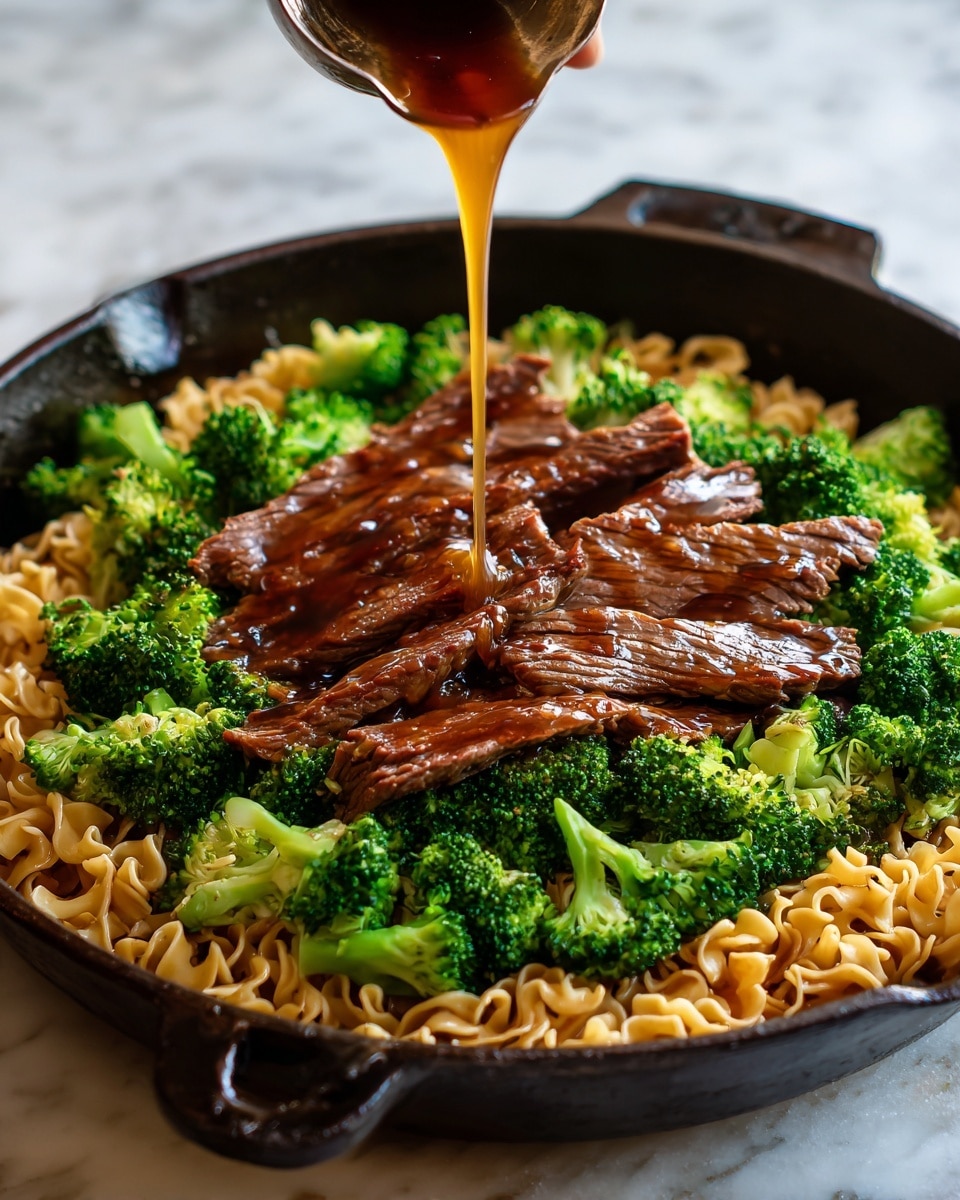 A close-up view of a black cast iron pan filled with cooked yellow noodles as the base layer, topped with bright green broccoli florets scattered evenly, and strips of glazed brown beef placed on top. A golden-brown sauce is being poured over the dish, adding shine and moisture to the beef and broccoli. The pan is on a white marbled surface, creating a clean contrast with the dark pan and colorful food. photo taken with an iphone --ar 4:5 --v 7